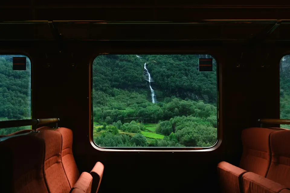 Waterfall on a green hillside seen through the window of a vintage train